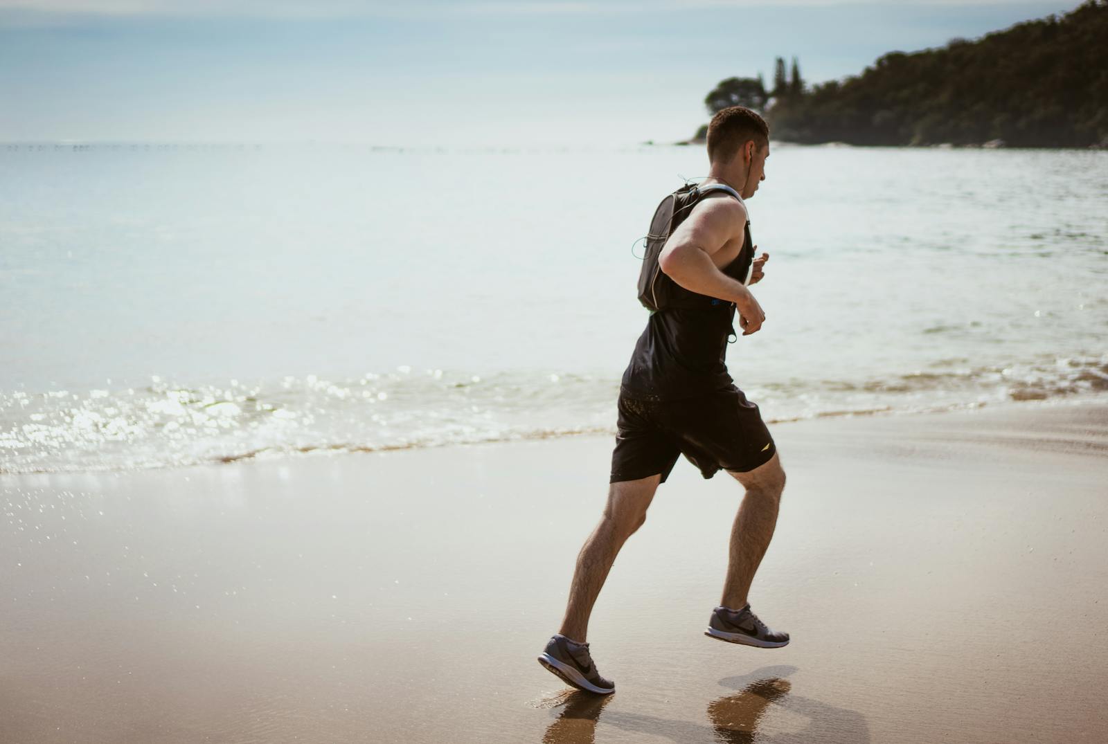 Man running along the beach enjoying fitness and freedom by the ocean waves.