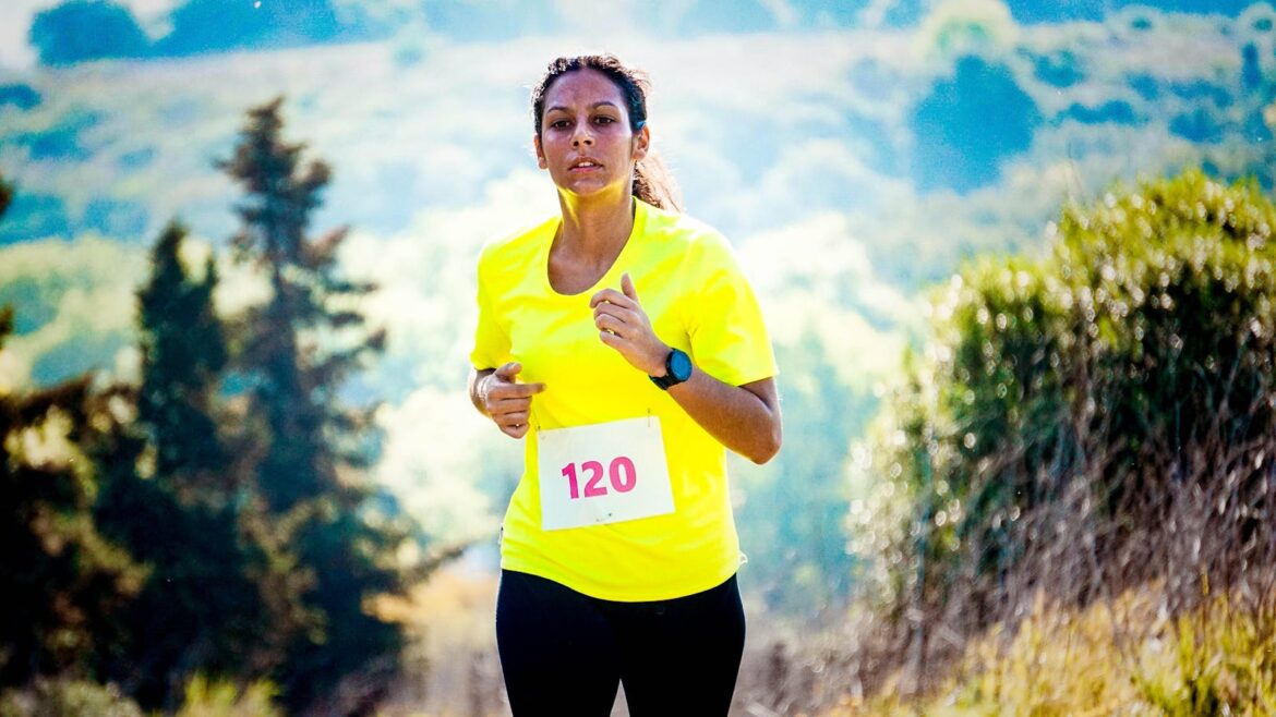 A fit woman running a marathon in a vibrant outdoor landscape, wearing a bright yellow shirt.