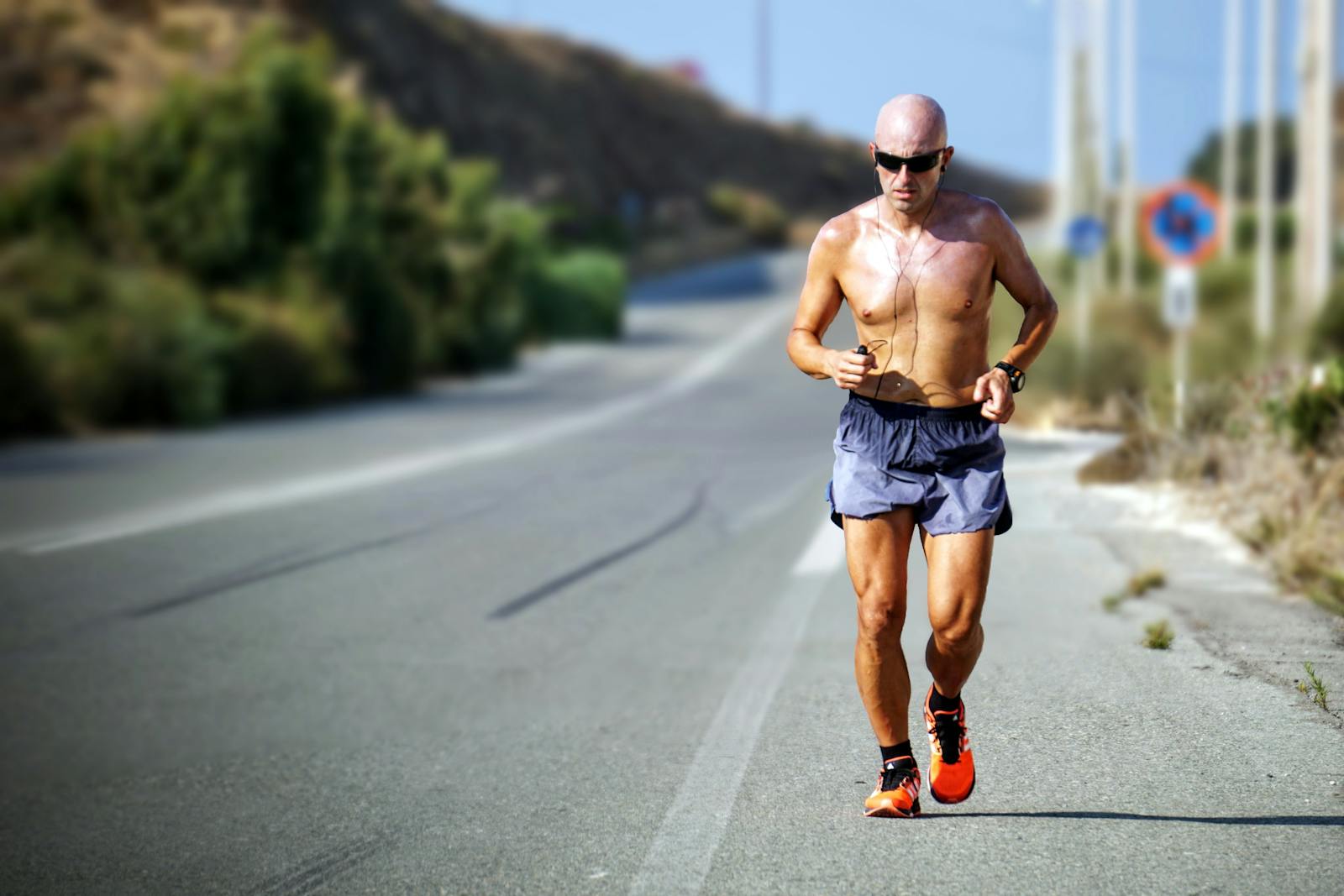 A determined jogger runs on a sunlit road in Crete, Greece. Perfect for fitness and travel themes.