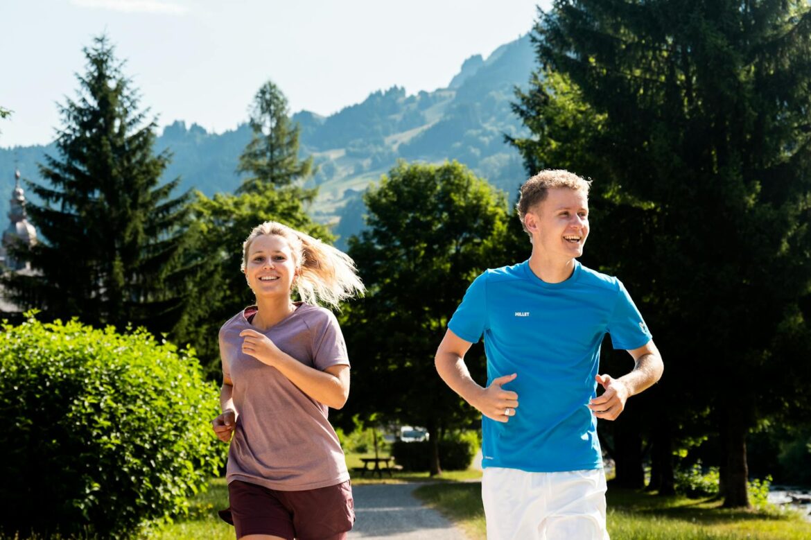 A cheerful couple jogging on a sunny day in a picturesque mountain landscape.
