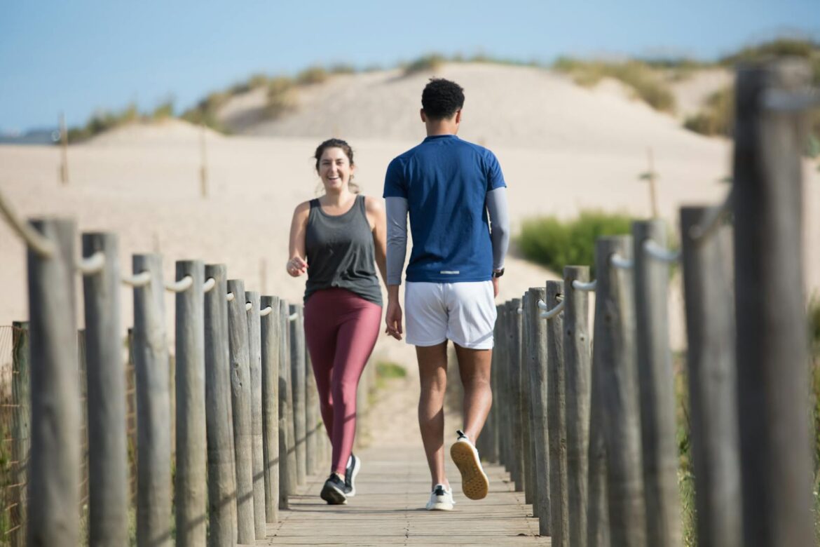 A couple enjoys jogging on a sunny beach boardwalk in Portugal, capturing a moment of fitness and leisure.
