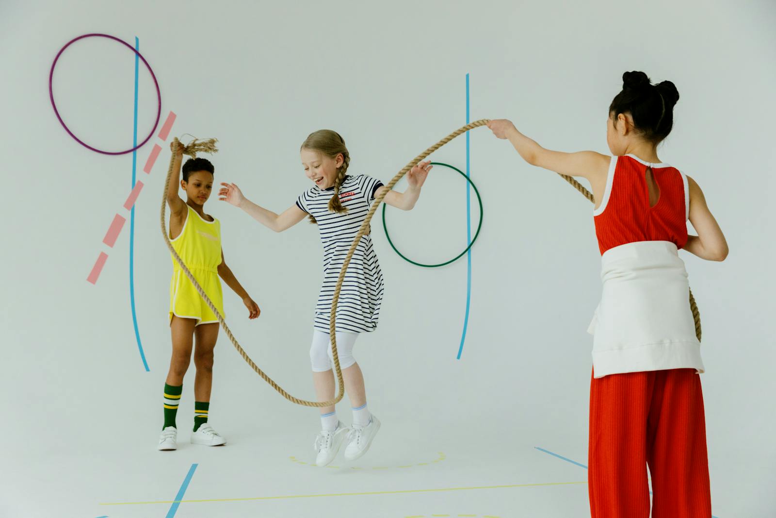 Three diverse children having fun playing jump rope indoors, enjoying energetic activity.