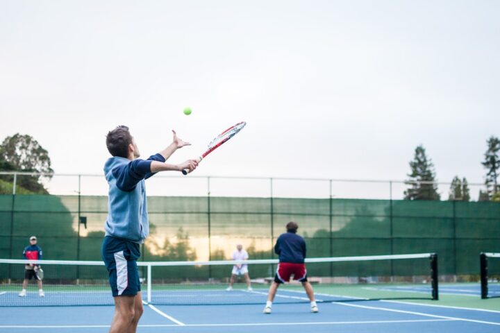 My friends playing a tennis match in the afternoon sun.