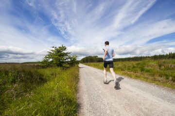 Hardlopers op een vlakke polderweg langs een dijk in het rivierenlandschap