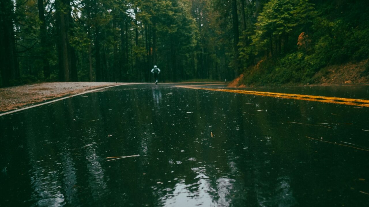 Hardloper op een nat wegdek bij grijs, winderig weer