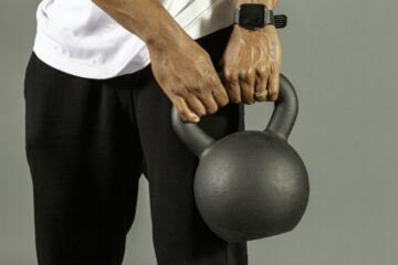 Oudere hardloper doet een krachtoefening met een kettlebell op een grasveld