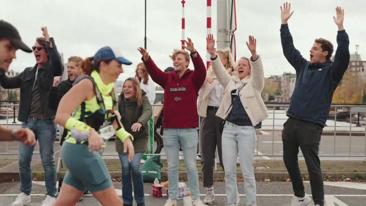 Supporters juichen een loopster toe langs het parcours van de marathon van Amsterdam