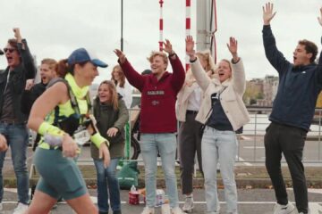 Supporters juichen een loopster toe langs het parcours van de marathon van Amsterdam