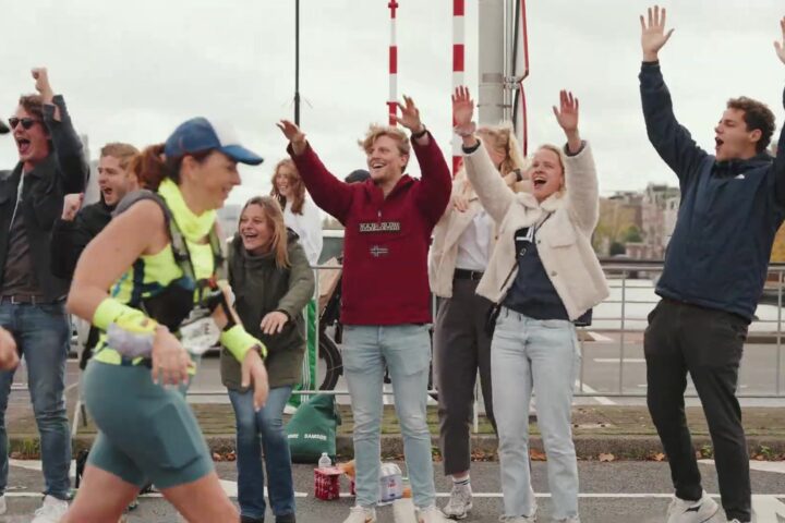 Supporters juichen een loopster toe langs het parcours van de marathon van Amsterdam
