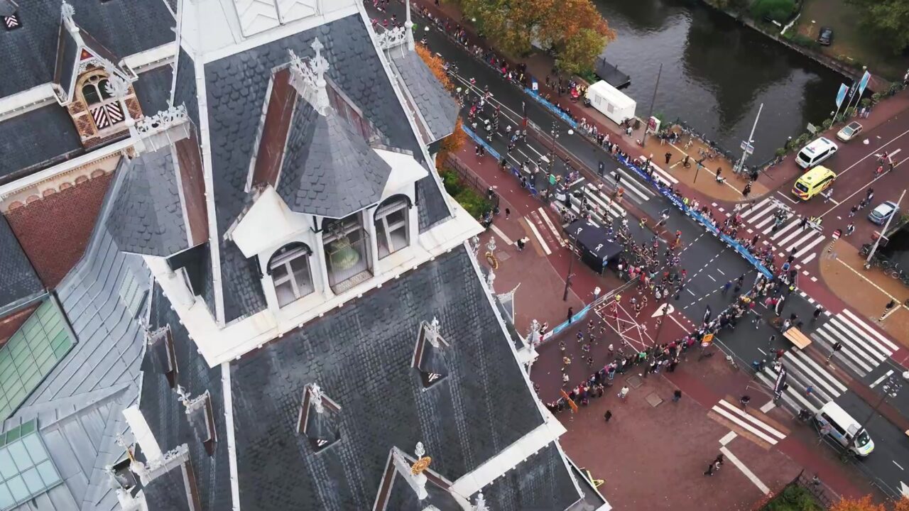Lopers van de TCS Amsterdam Marathon van bovenaf gezien op een kruispunt langs de gracht