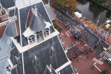 Lopers van de TCS Amsterdam Marathon van bovenaf gezien op een kruispunt langs de gracht