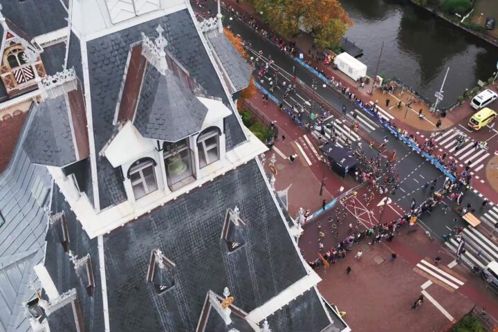 Lopers van de TCS Amsterdam Marathon van bovenaf gezien op een kruispunt langs de gracht