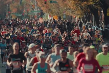 Een breed veld marathonlopers in een straat met herfstbomen tijdens de marathon van New York