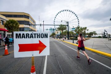 Marathonloper op een afgezet parcours langs een bord met de looprichting