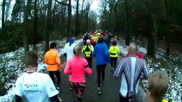 Lopers op een besneeuwd bospad tijdens de Midwinter Marathon in Apeldoorn