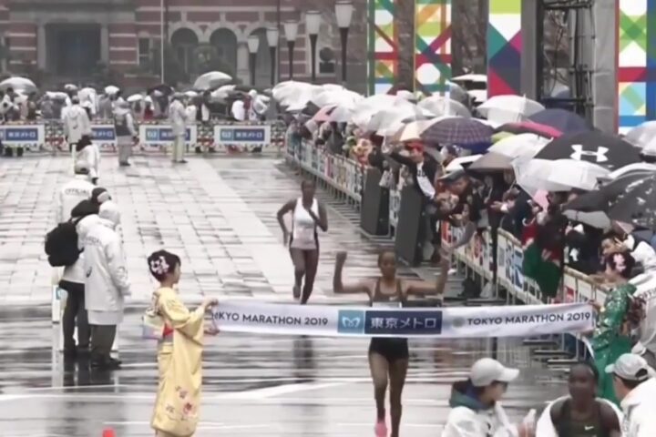 Ruti Aga komt in de regen als winnares over de finish van de marathon van Tokio in 2019