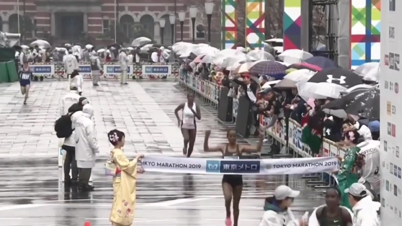Ruti Aga komt in de regen als winnares over de finish van de marathon van Tokio in 2019