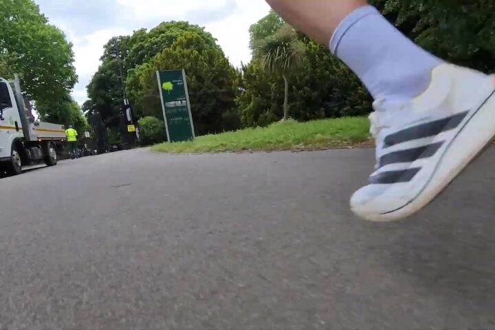 Close-up van een witte Adidas raceschoen tijdens het hardlopen op asfalt